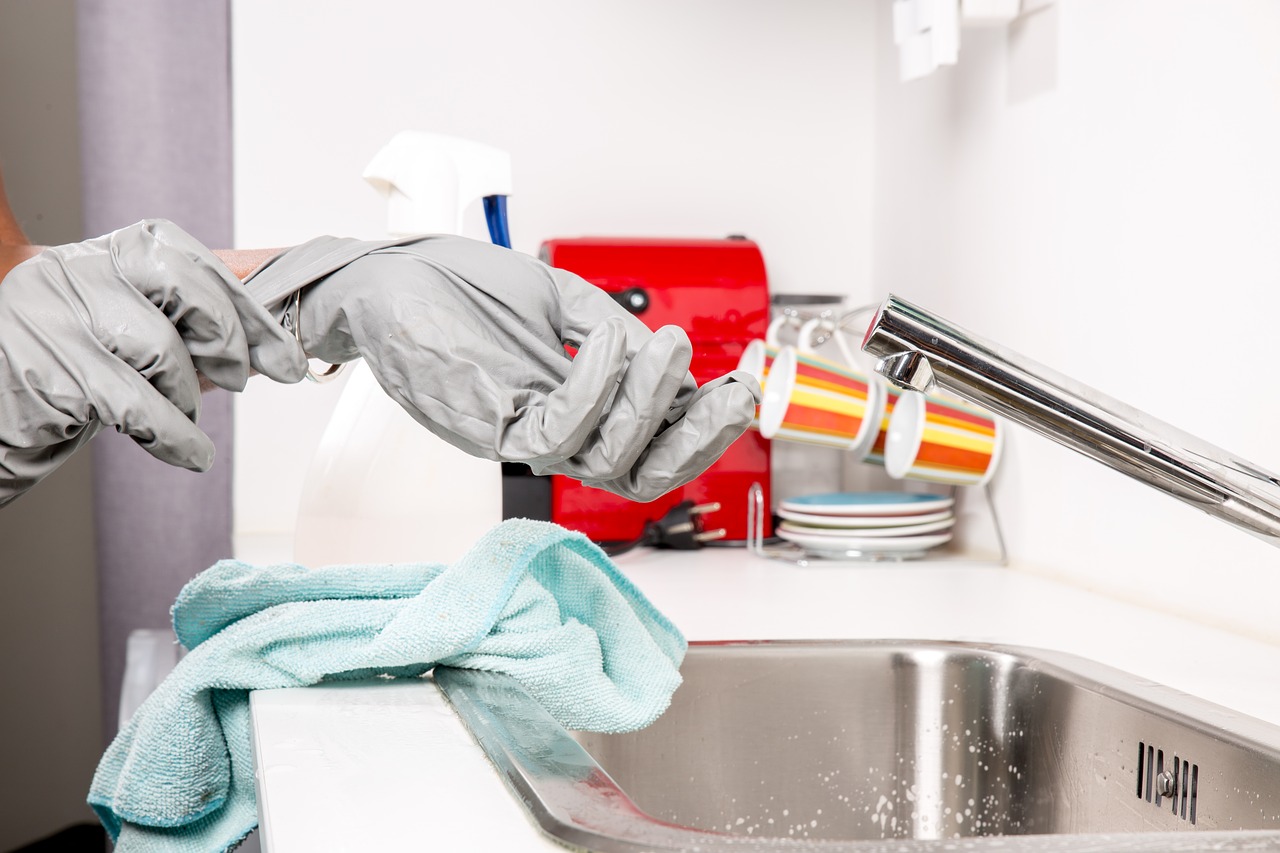 washing dishes with gloved hands in kitchen